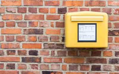 yellow german mailbox on brick wall