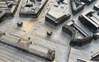 Detailansicht eines Stadtmodells mit verschiedenen Gebäuden und Straßen in Bronze.